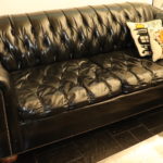Vintage Black Leather Like Sofa With Tufted Back And Stud Trim Along Edges Tear On Arm