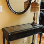 Small Decorative Console Table With Glass Top And Stenciled Scrolled Detail And Wall Mirror